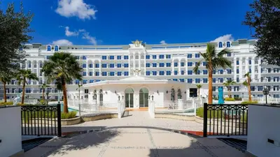a large white building with palm trees in front of it at Vincitore Benessere - Arjan by Golden Casa in Dubai
