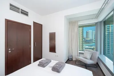 a bedroom with a bed and a chair and a window at 2BR 29Blvd Balcony Fountain View in Dubai