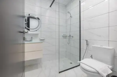 a white bathroom with a shower and a toilet at StayShort - Stunning 2BR Apartment in Jebel Ali Village in Dubai