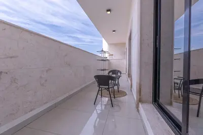 a balcony with chairs and tables in a building at StayShort - Stunning 2BR Apartment in Jebel Ali Village in Dubai
