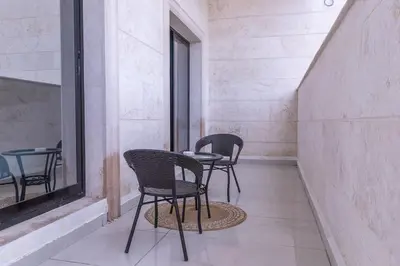 a patio with three chairs and a table and a window at StayShort - Stunning 2BR Apartment in Jebel Ali Village in Dubai