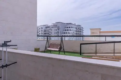 a balcony with a hammock and a view of buildings at StayShort - Stunning 2BR Apartment in Jebel Ali Village in Dubai