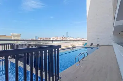 a swimming pool with chairs next to a building at StayShort - Stunning 2BR Apartment in Jebel Ali Village in Dubai