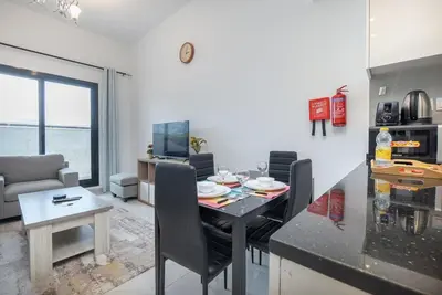 a kitchen and living room with a table and a dining room at StayShort - Stunning 2BR Apartment in Jebel Ali Village in Dubai