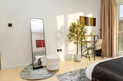 a bedroom with a mirror and a chair and a table at Escape24 Chic 1BR in Al Furjan near Metro in Dubai
