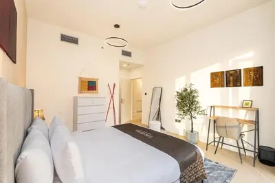 a bedroom with a white bed and a chair at Escape24 Chic 1BR in Al Furjan near Metro in Dubai