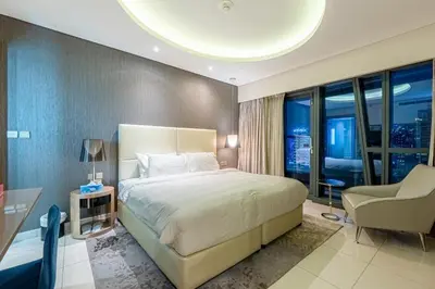 a bedroom with a large bed and a chair in it at Venetian - High Floor 2BR Residence with Incredible Burj View in Dubai