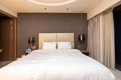 a bedroom with a large white bed with two lamps at Venetian - High Floor 2BR Residence with Incredible Burj View in Dubai