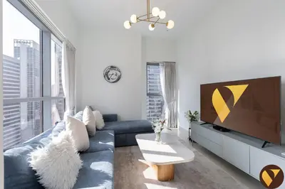 a living room with a blue couch and a tv at Vogue Downtown Bellevue Towers near Burj Khalifa and Dubai Mall, One Bedroom Apartment with City View, Full Access to all Amenities in Dubai
