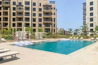 a large swimming pool with white chairs and buildings at Frank Porter - Rahaal 2 in Dubai