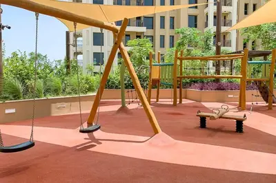 a playground with swings and a bench in a building at Frank Porter - Rahaal 2 in Dubai