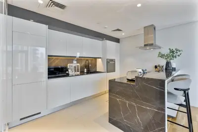 a kitchen with white cabinets and a counter at Mira Holiday Homes - Sky High Bliss at Bluewaters Residence 3 Ain View in Dubai