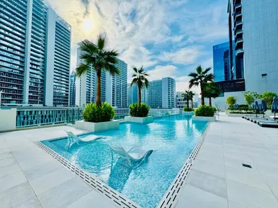 a swimming pool with two chairs and palm trees on a building at Venduras - Luxe Studio, City Views , Sterling by Omniyat in Dubai