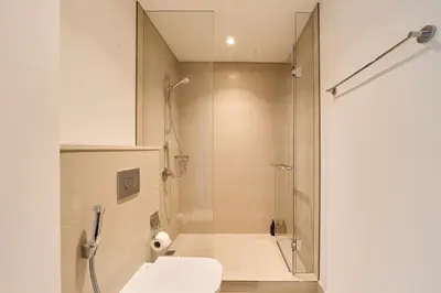a bathroom with a shower and a toilet and a sink at Stunning 2BR Skyline Stay With Full Burj Khalifa View in Dubai