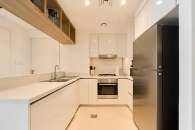 a kitchen with white cabinets and a stainless steel refrigerator at Stunning 2BR Skyline Stay With Full Burj Khalifa View in Dubai