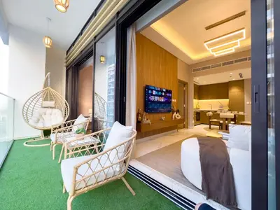 a room with a large window with chairs and a television at Meydan Luxury Stylish 2BR with Pool & City Views in Dubai