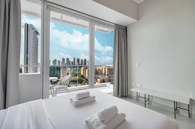 a bedroom with a large white bed and a large window at StayMada - Ocean Heights Panoramic Beach Views in Dubai