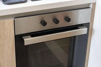 a stove top oven sitting under a counter at StayMada - Peninsula Luxury Apartment with Balcony in Dubai