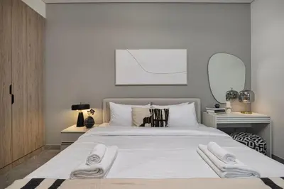 a bedroom with a large white bed with two towels on it at StayMada - Peninsula Luxury Apartment with Balcony in Dubai