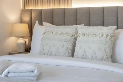a white bed with white pillows and a headboard at The Imperial Burj View by NAMUVE at 29 Boulevard in Dubai