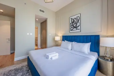 a large bed with a blue headboard in a room at Locations I Downtown Dubai I Premium 3BR Apartment I Luxury & Modern Interiors I Stunning Burj Khalifa Views I Steps from Dubai Mall & Dubai Fountain in Dubai