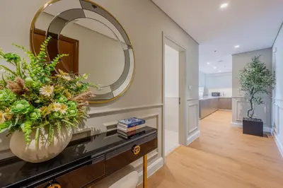 a hallway with a large mirror and a vase with flowers at Locations I Downtown Dubai I Premium 3BR Apartment I Luxury & Modern Interiors I Stunning Burj Khalifa Views I Steps from Dubai Mall & Dubai Fountain in Dubai