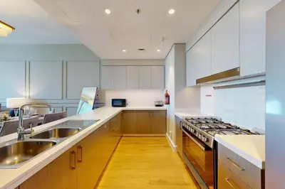 a kitchen with white cabinets and stainless steel appliances at Locations I Downtown Dubai I Premium 3BR Apartment I Luxury & Modern Interiors I Stunning Burj Khalifa Views I Steps from Dubai Mall & Dubai Fountain in Dubai
