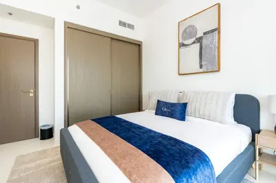 a bedroom with a large bed with a blue pillow on it at CitiHome - Elie Saab Luxury 2BR - Sea View in Dubai
