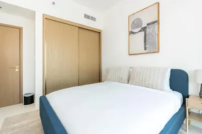 a bedroom with a white bed and a wooden door at CitiHome - Elie Saab Luxury 2BR - Sea View in Dubai