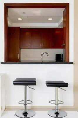 a kitchen with two bar stools at a counter at Skyline 43 - Penthouse Burj Khalifa View & Pool in Dubai