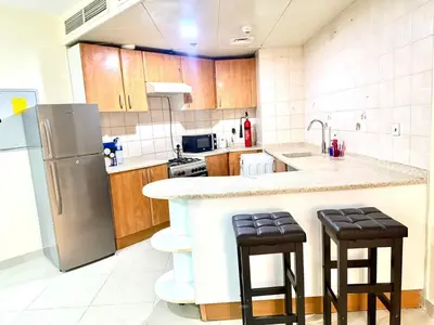 a kitchen with a refrigerator and two bar stools at Dubai gate 1 in Dubai