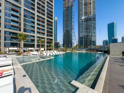 a large swimming pool in a city with tall buildings at Waterfront 1BR with Canal Views in Peninsula One in Dubai