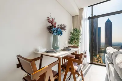 a dining room with a table and chairs and a window at Waterfront 1BR with Canal Views in Peninsula One in Dubai