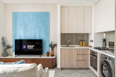 a kitchen with white cabinets and a tv on a counter at Waterfront 1BR with Canal Views in Peninsula One in Dubai