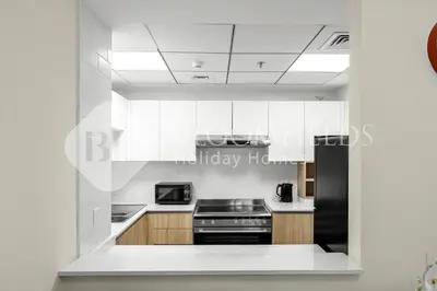 a white kitchen with a stove and a microwave at Bloomfields Canal View 2Br Apt Canal Business in Dubai