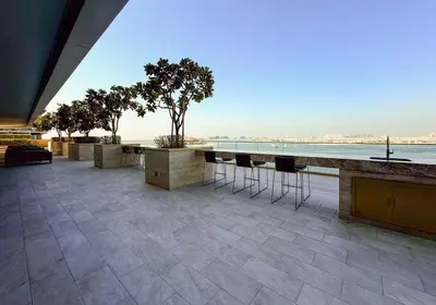 a patio with bar stools and a view of the ocean at Zapbed House -Elegant 1 BR Apartment Grand Bleu Emaar Beachfront in Dubai