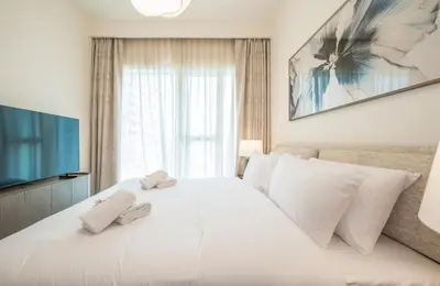 a bedroom with a large white bed with two towels at Zapbed House -Elegant 1 BR Apartment Grand Bleu Emaar Beachfront in Dubai