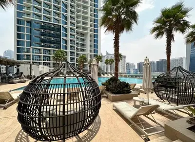 a view of a pool with palm trees and buildings at DAMAC MAISON PRIVE SLEEP FOUr in Dubai