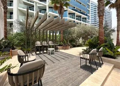 a patio with chairs and tables in front of a building at DAMAC MAISON PRIVE SLEEP FOUr in Dubai