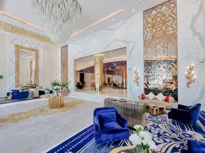a large lobby with blue chairs and a chandelier at DAMAC MAISON PRIVE SLEEP FOUr in Dubai