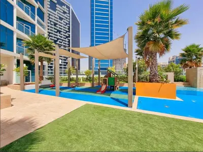 a pool with a hammock and palm trees and buildings at DAMAC MAISON PRIVE SLEEP FOUr in Dubai
