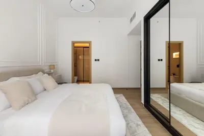 a white bedroom with a large white bed and a mirror at Brand New 2BR, Circle Mall View, Great Pool & Gym in Dubai