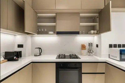 a kitchen with white cabinets and a stove top oven at Brand New 2BR, Circle Mall View, Great Pool & Gym in Dubai