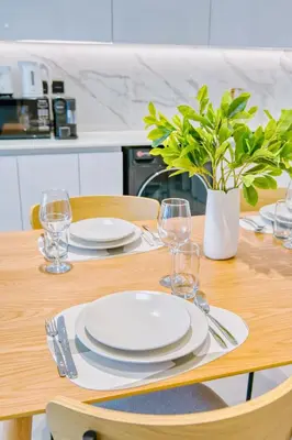 a wooden table with plates and wine glasses on it at PVH - Binghatti Lavender - Tranquil Modern 1BR - Near JVC Community Park in Dubai