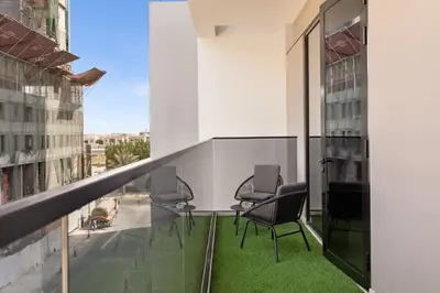 a balcony with chairs and a view of a building at Stylish 2 Bedrooms, Pool, Gym & Family-Friendly in Dubai