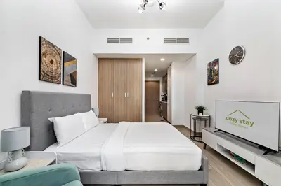 a bedroom with a large white bed and a television at Stylish Studio in Nad Al Sheba in Dubai