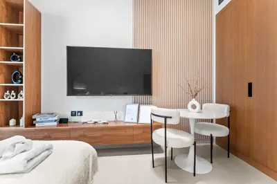a bedroom with a tv and a table and chairs at Brand New Luxury Studio, Amazing Pool & Gym in Dubai