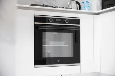 a black oven in a kitchen with white cabinets at Chic 1BR Getaway, Sleeps 4, Stunning Pool Views in Dubai
