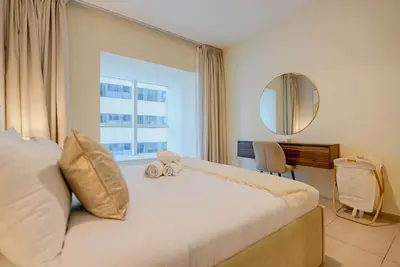 a bedroom with a bed with a mirror and a window at TRPS - Elite Residence, Dubai Marina - Modern High-Rise, Near Popular Sites, Partial Sea View in Dubai