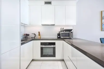 a white kitchen with white cabinets and a microwave at Newly Furnished Apt in District 1 in Dubai